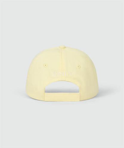 Image 5: Achterzijde van een pet in de kleur Butter Yellow met het JOSH V logo op de achterkant, weergegeven op een lichtgrijze achtergrond