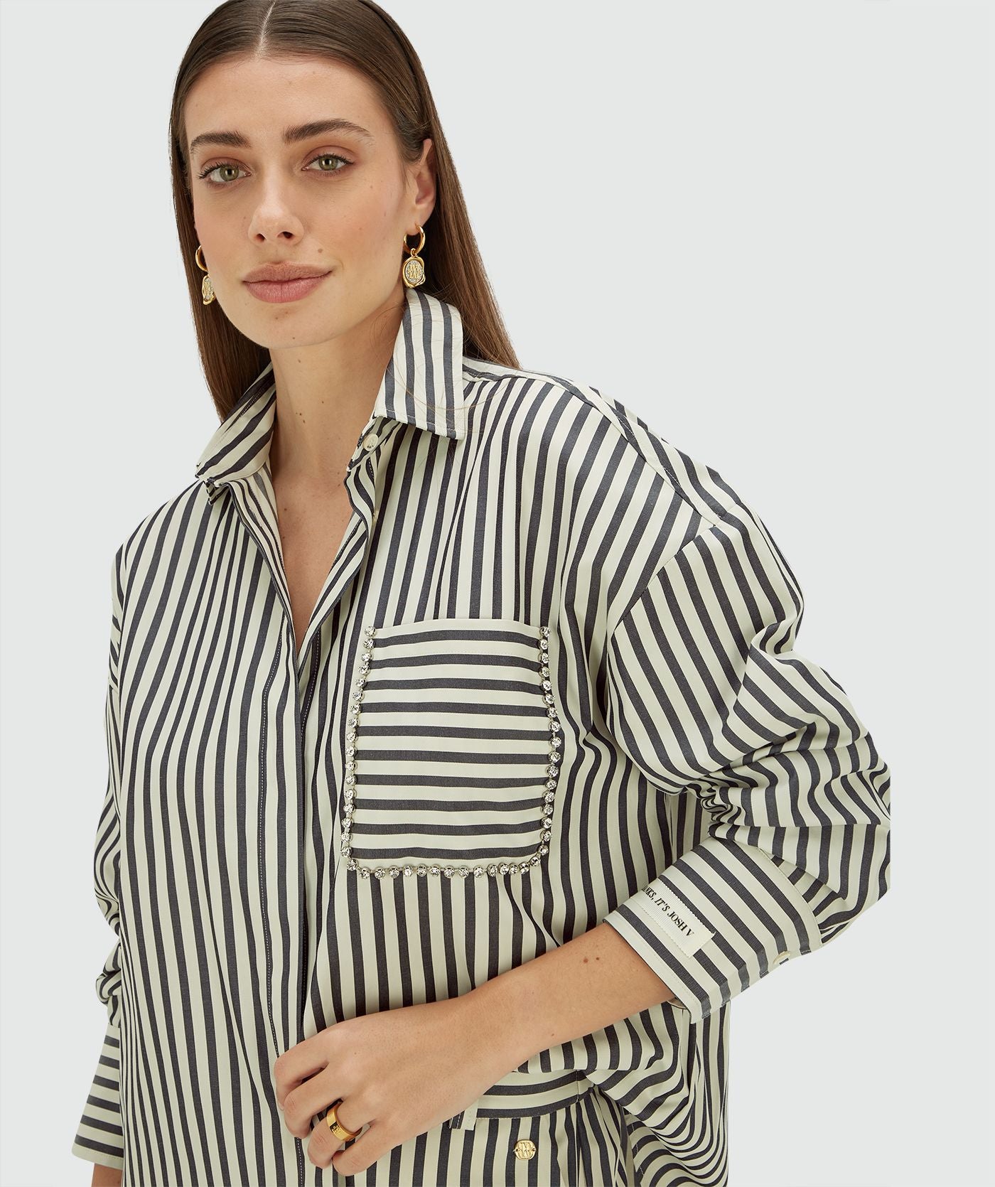 Image 2: Model draagt een oversized blouse met strepen in de kleur Blue Stripe met strass steentjes rond de borstzak