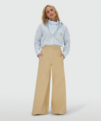 Image 1: Het model draagt een mid rise wide leg pantalon in de kleur Light Camel, voorzien van verstelbare knopen in de tailleband