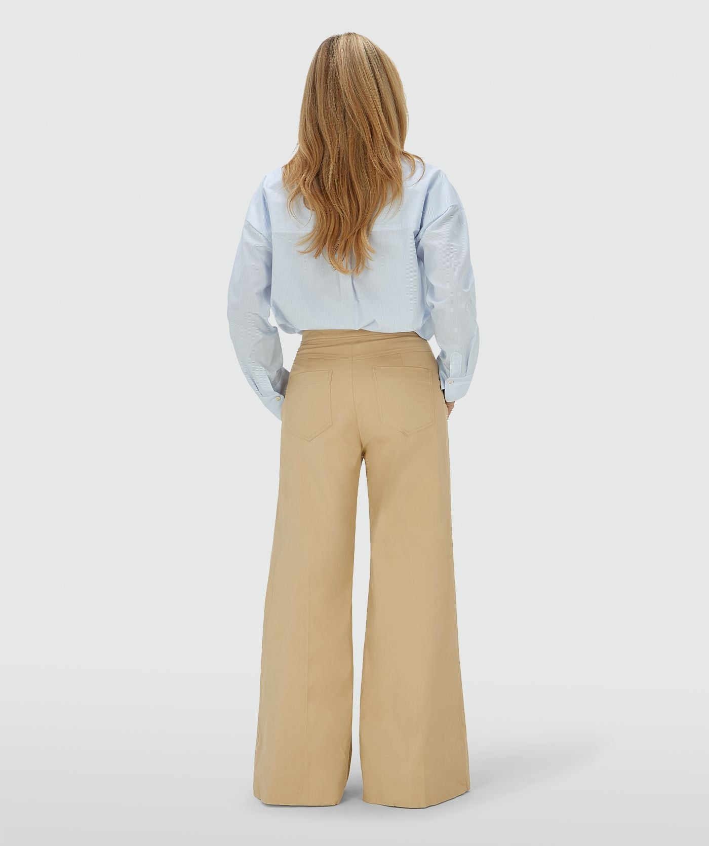 Image 5: Achteraanzicht van een model in een mid rise wide leg pantalon in de kleur Light Camel, voorzien van verstelbare knopen in de tailleband
