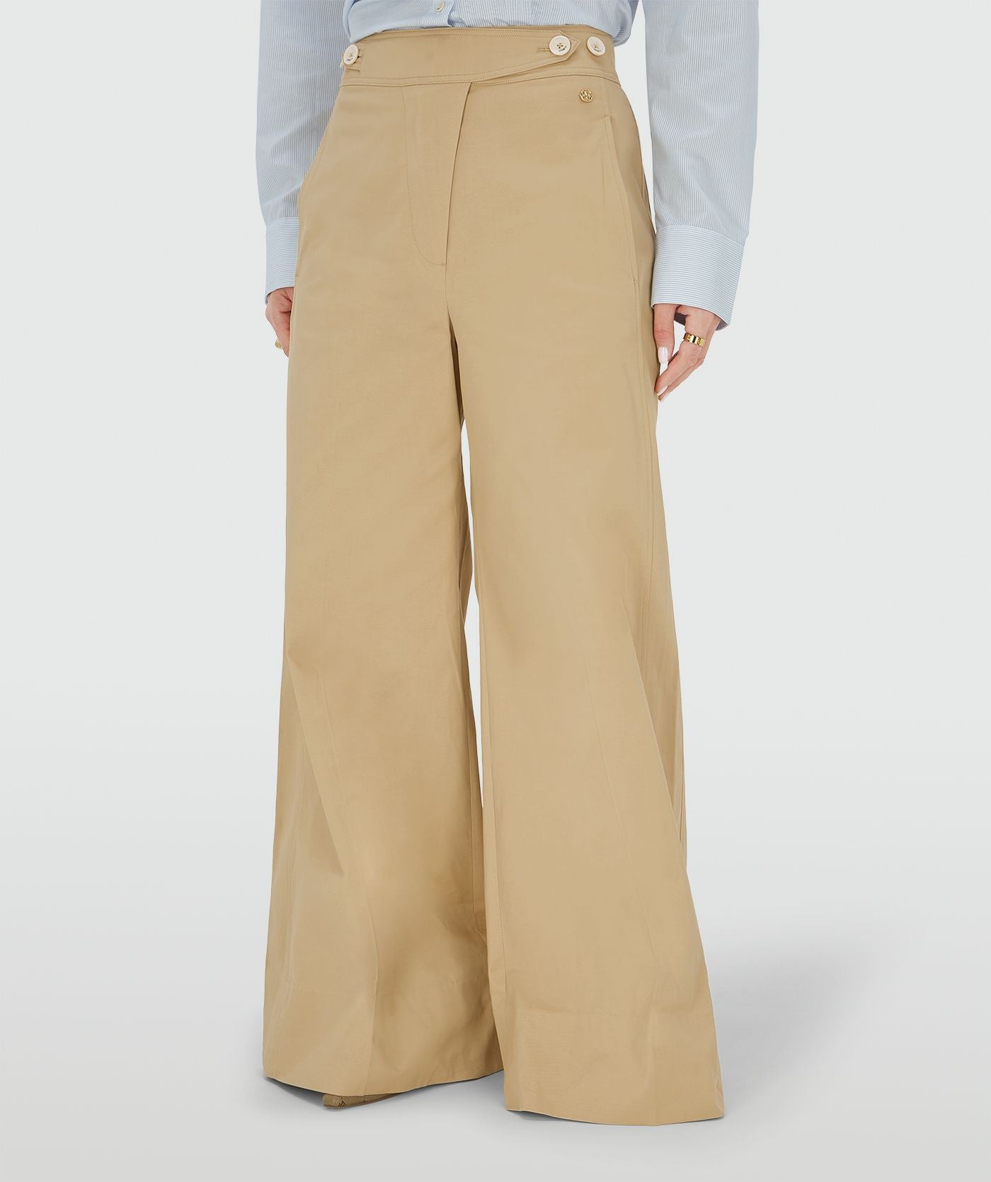 Image 2: Ingezoomd beeld waarin een model een mid rise wide leg pantalon draagt in de kleur Light Camel, voorzien van verstelbare knopen in de tailleband