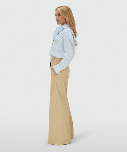 Image 3: Zijaanzicht van een model in een mid rise wide leg pantalon in de kleur Light Camel, voorzien van verstelbare knopen in de tailleband